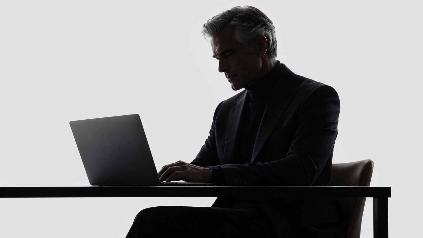 A man alone at a laptop in an empty studio, about to send.